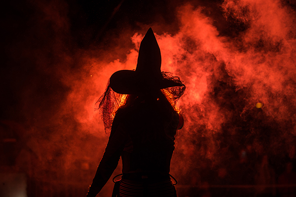 A shadow of a witch against a backdrop of fire