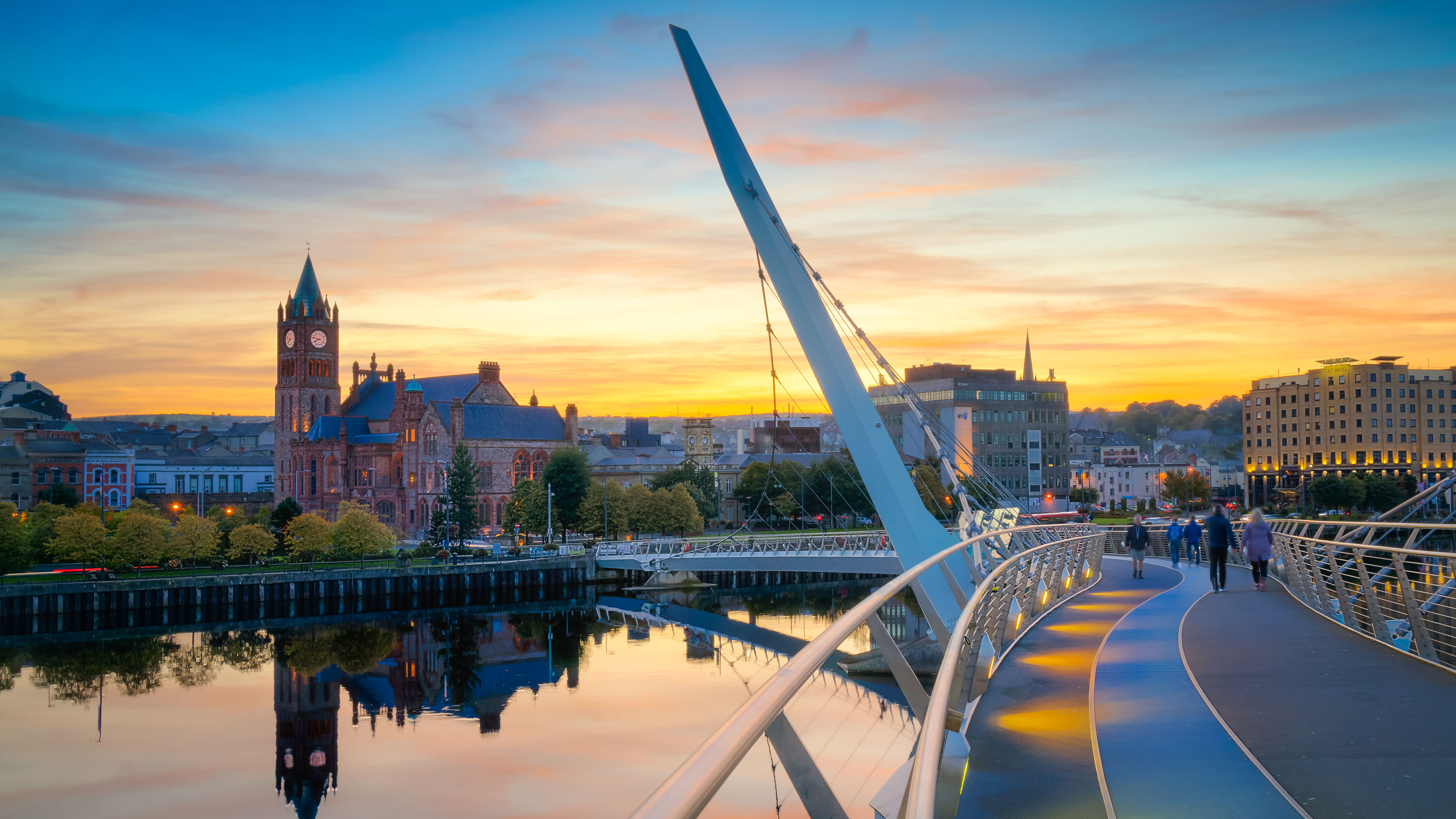The Peace Bridge and Guildhall at sunset in Derry Londonderry, Northern Ireland—an iconic view featured on CIE Tours' Ireland vacations.