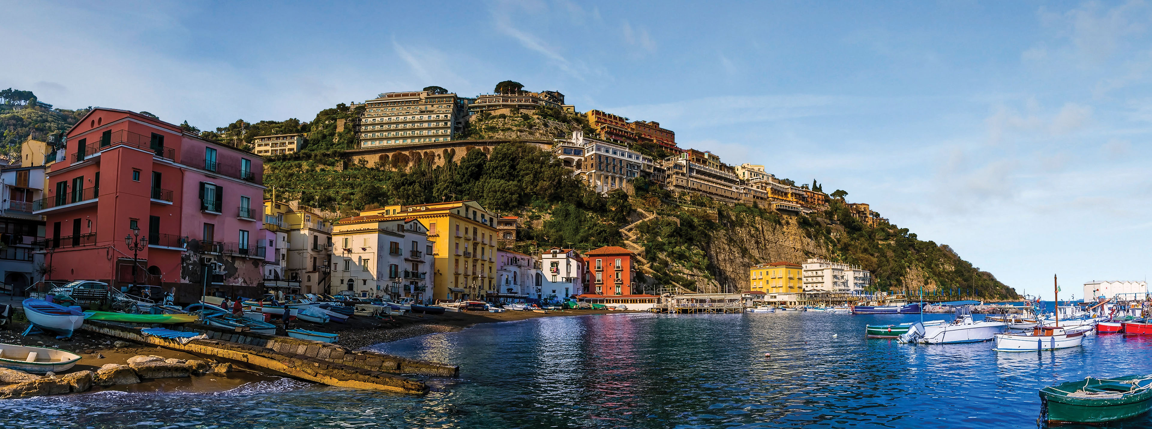 Colorful cliffside buildings and fishing boats in the Marina Grande of Sorrento, Italy, overlooking the Bay of Naples