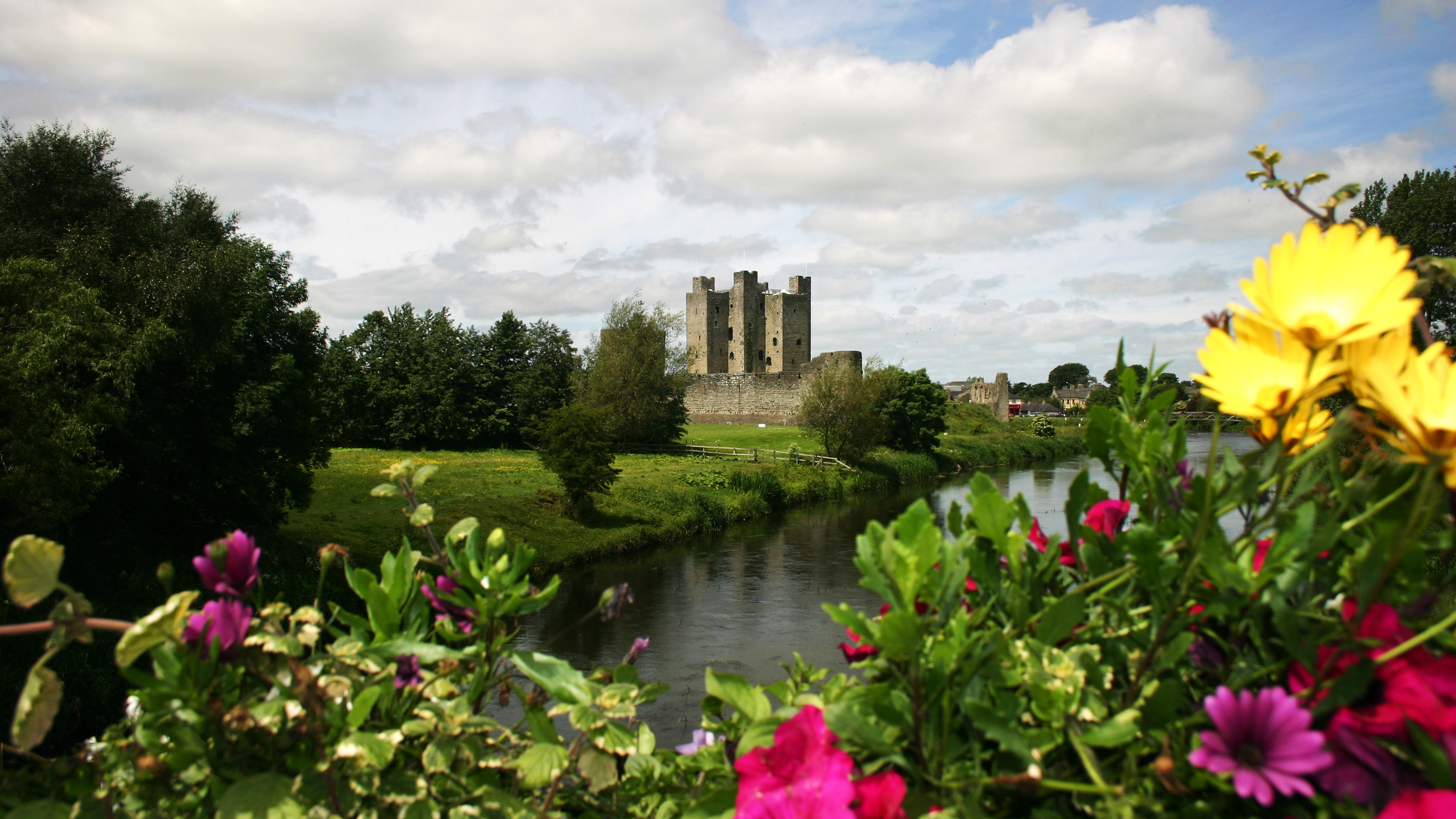 Trim Castle in Country Meath, Ireland, overlooking the River Boyne with vibrant garden flowers.
