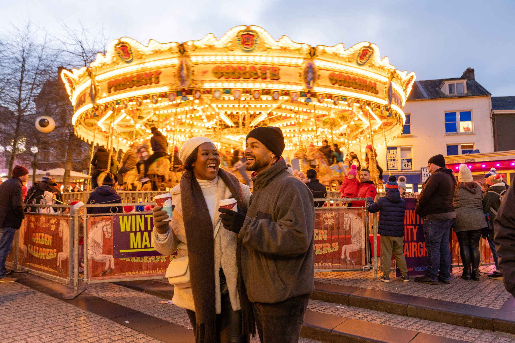 A couple in front of a festive merry-go-round