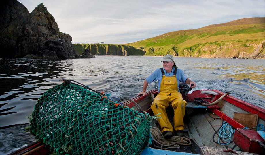 Fisherman on boat with nets in harbour at Glencolumbcille, County Donegal.