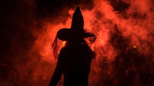 A shadow of a witch against a backdrop of fire