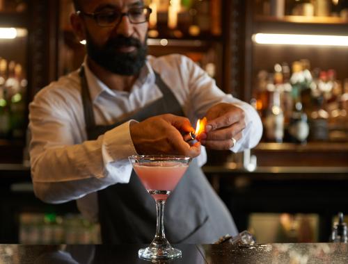 Bartender at the bar lighting a cocktail on fire
