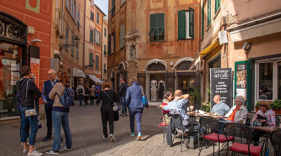 A street scene with people, old buildings, narrow streets, and a cafe.